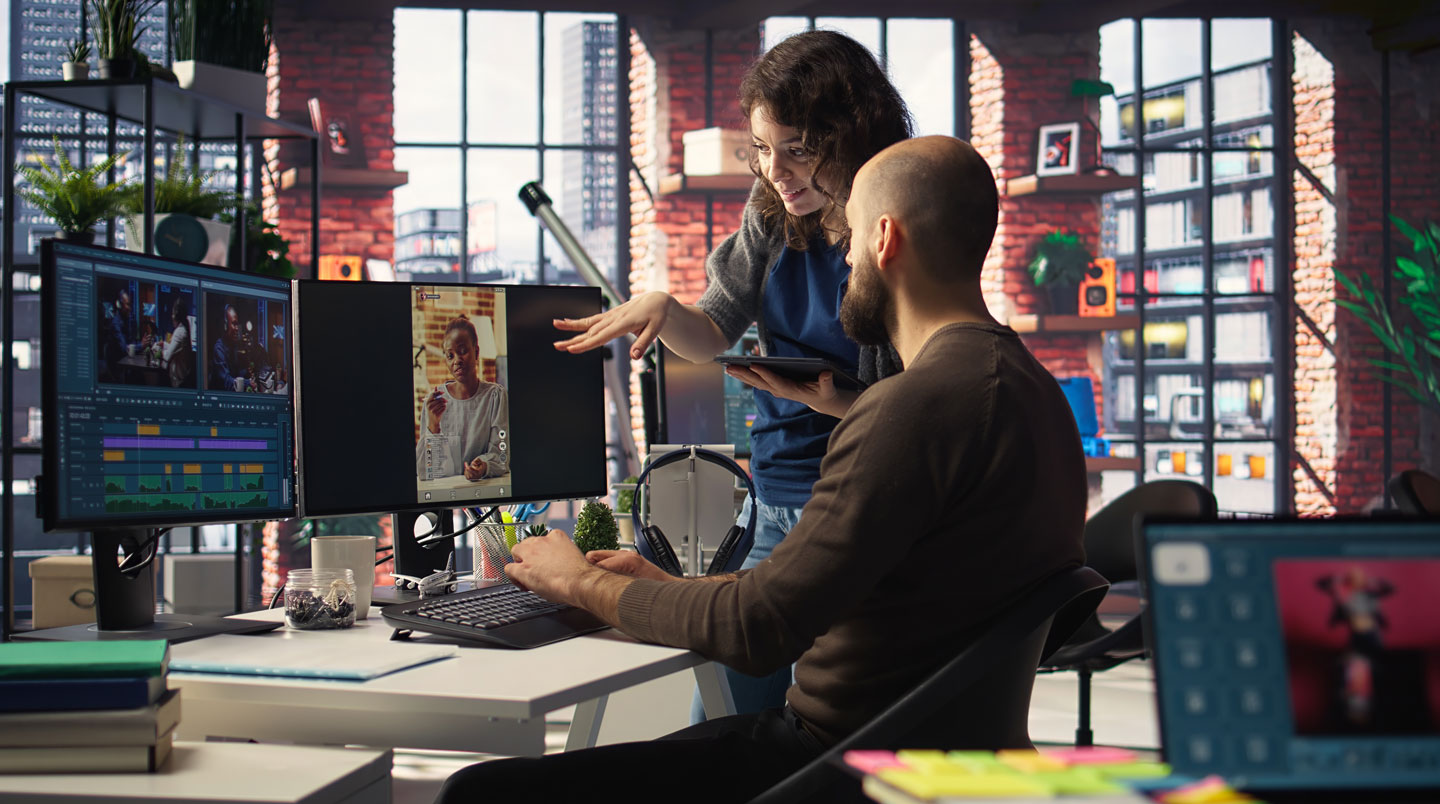 Two marketing team members collaborating on video content around laptop screen