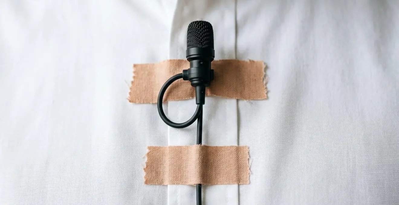 Close-up demonstration of professional lavalier microphone placement under clothing